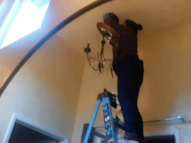 Electrician installing a chandelier in a Jenks residence
